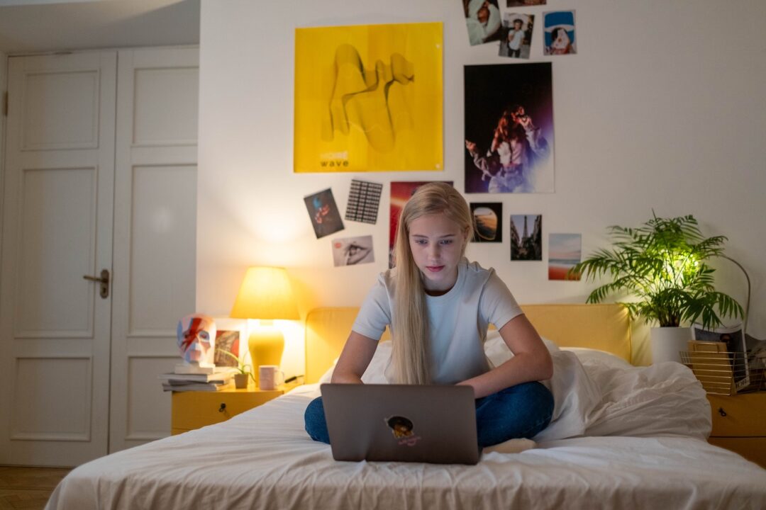 teen girl sitting on bed looking at computer tips for blending families with teenagers