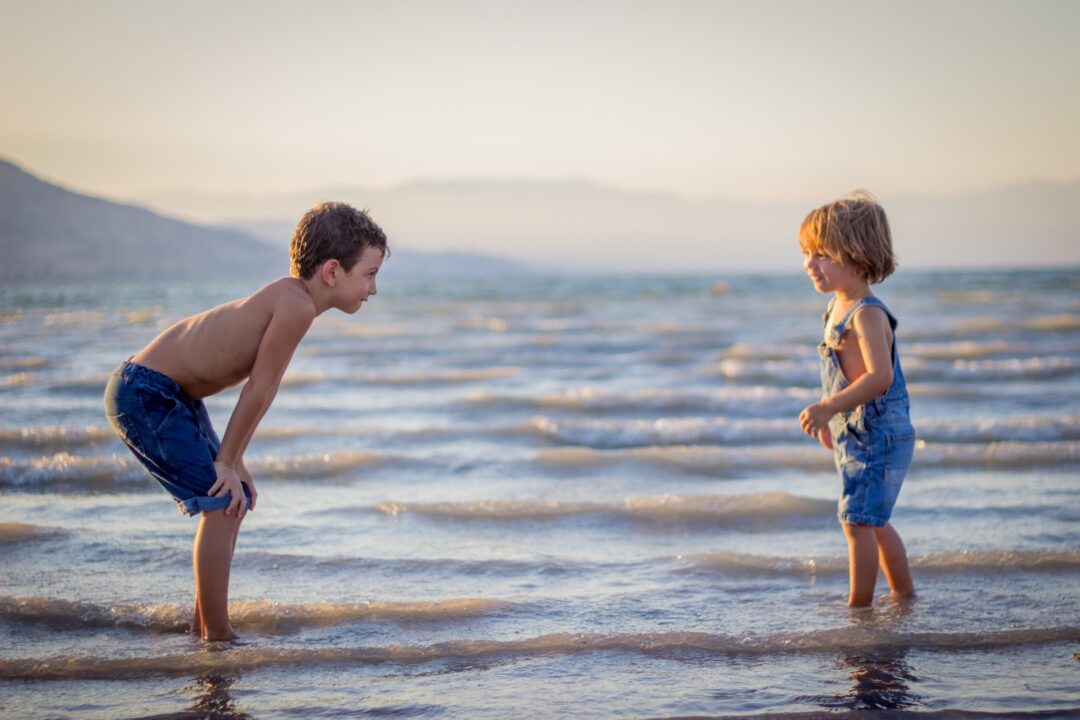 two young boys playing in shallow waves
